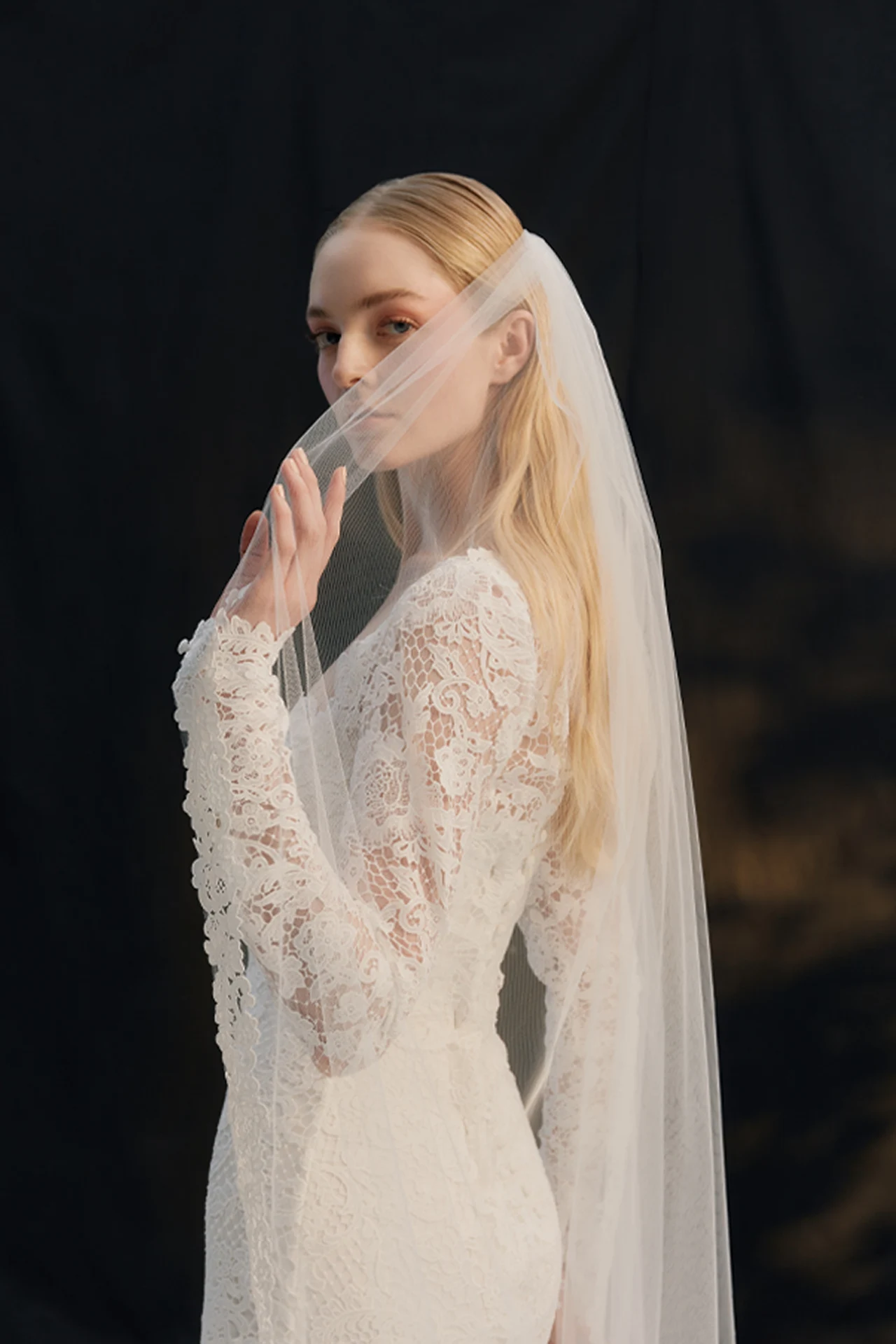 Bride with a lace veil against a dark background