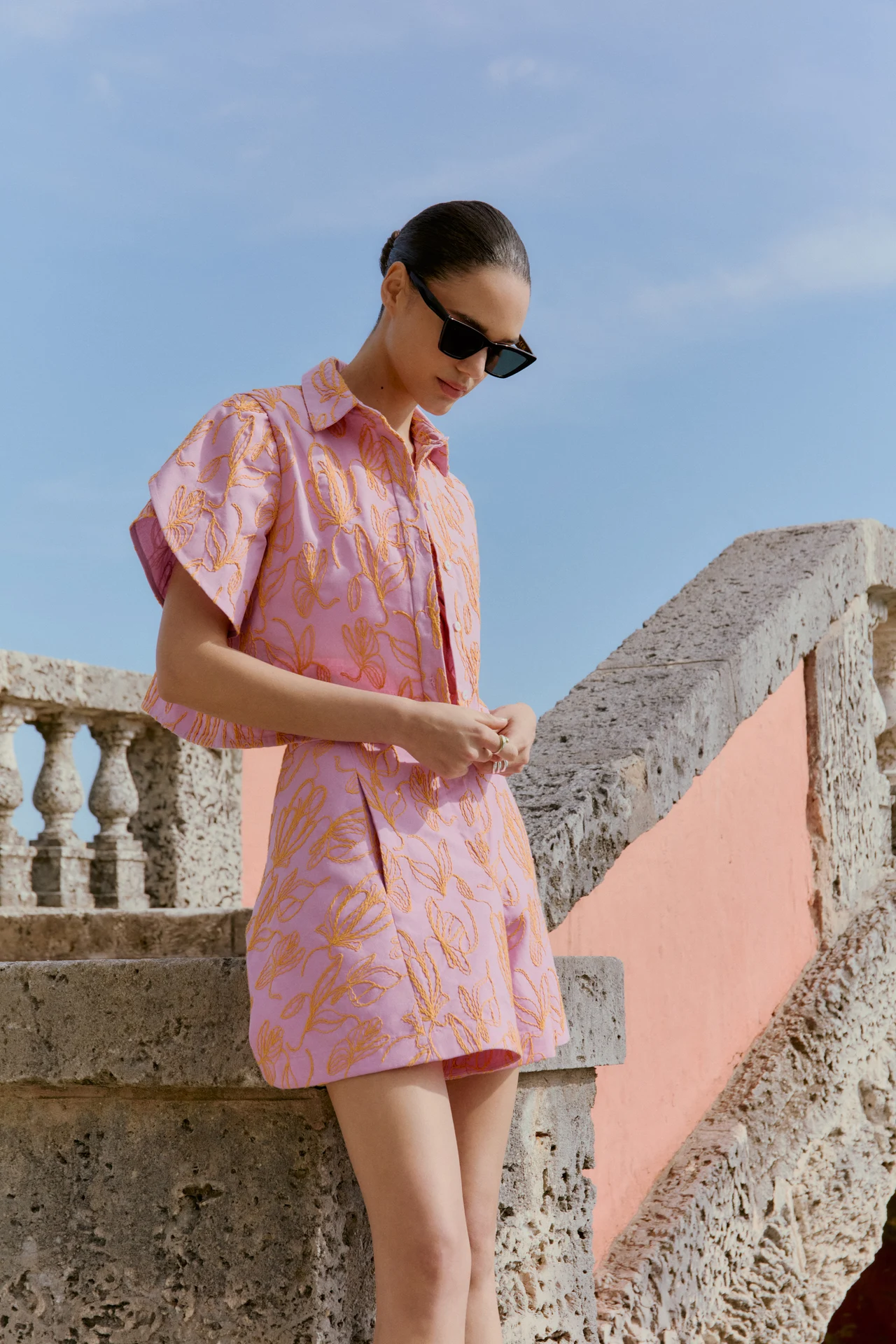Model in a pink printed outfit beside a stone terrace