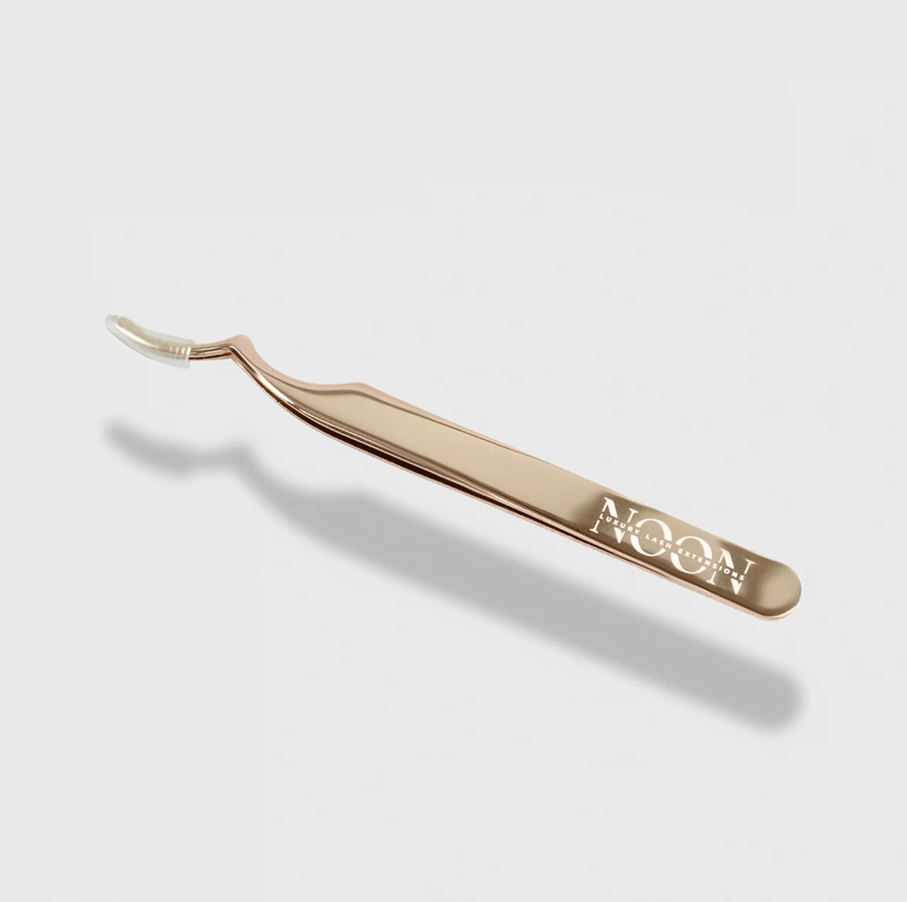 Gold eyelash applicator on a neutral background