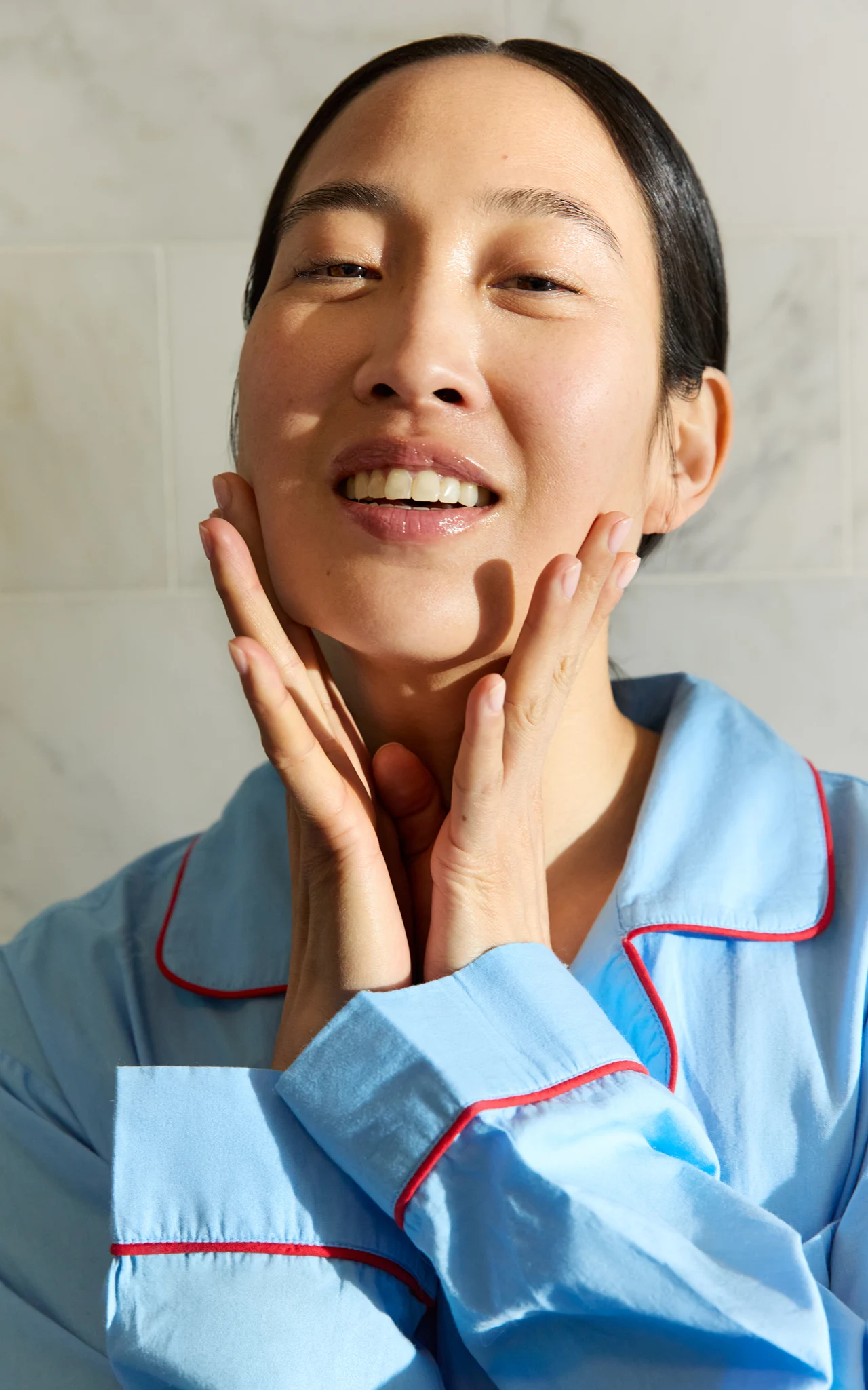Model in blue pajamas applying skincare