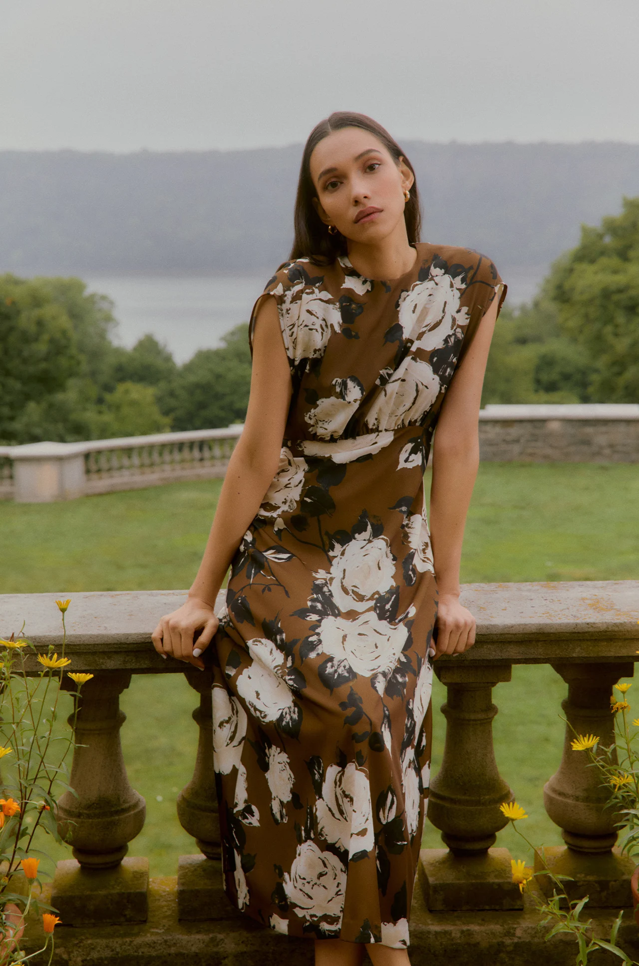 Model in a floral dress beside a stone balustrade