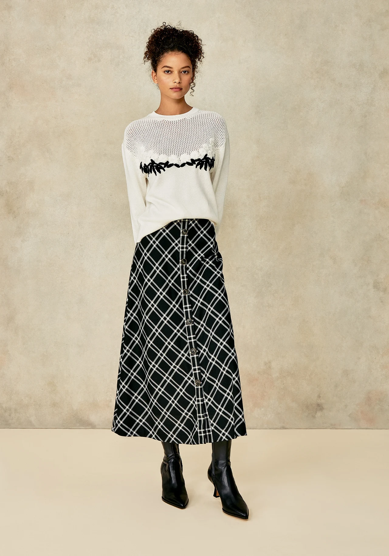 Model in a cream knit top and patterned skirt