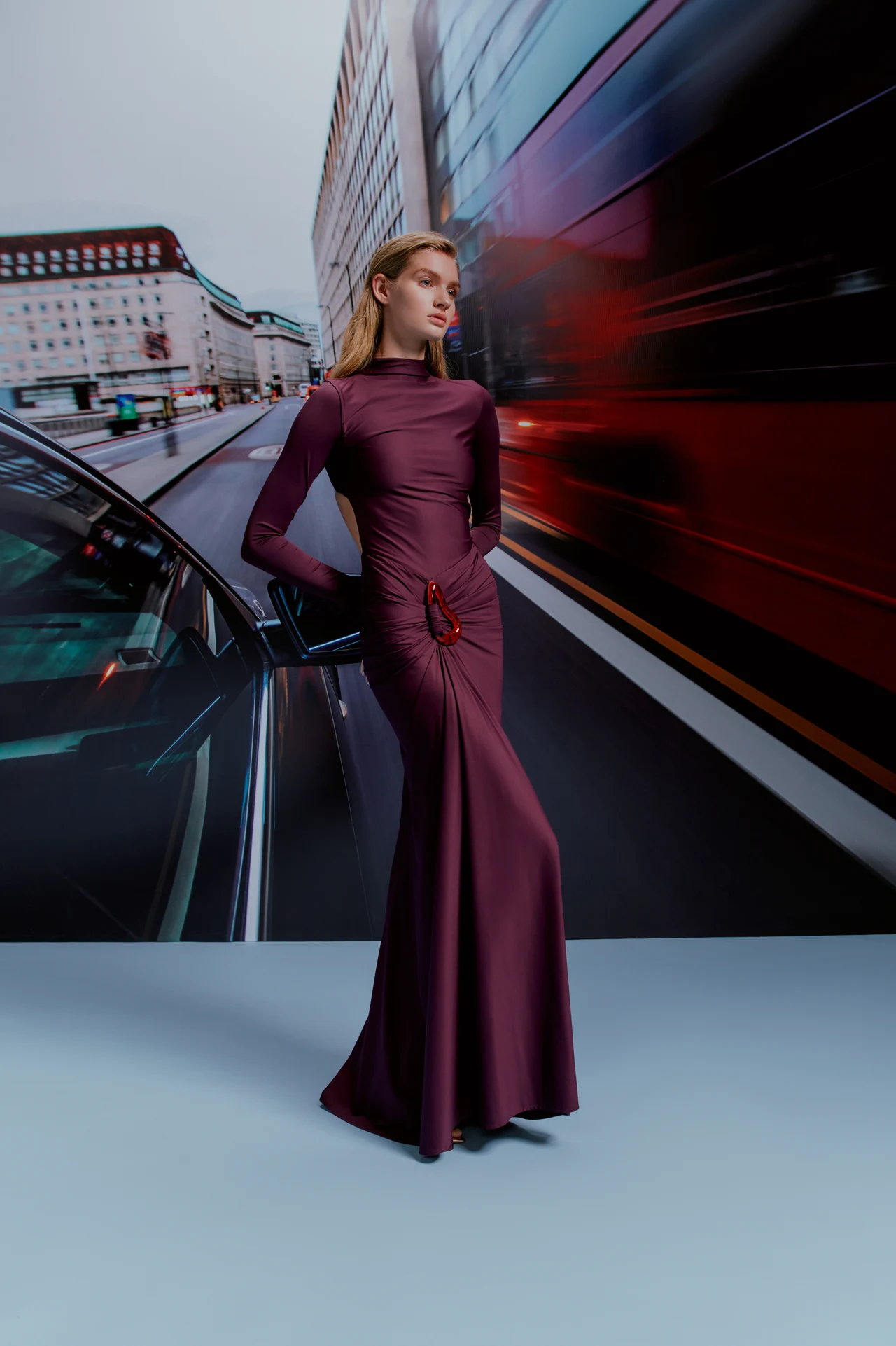 Model in a purple evening dress against a city backdrop